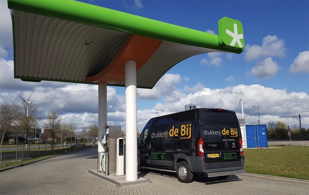 Zwarte bestelwagen bij laadstation met groen dak