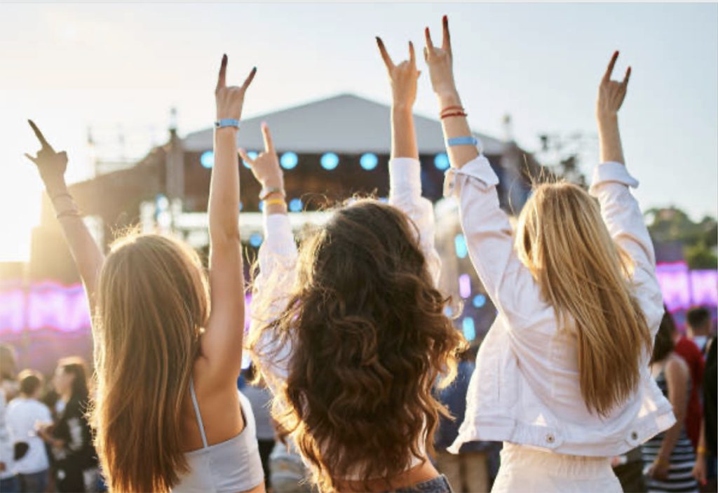 Mensen vieren feest op een muziekfestival bij zonsondergang.