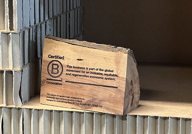 Houten B Corp certificaat op kartonnen plank.